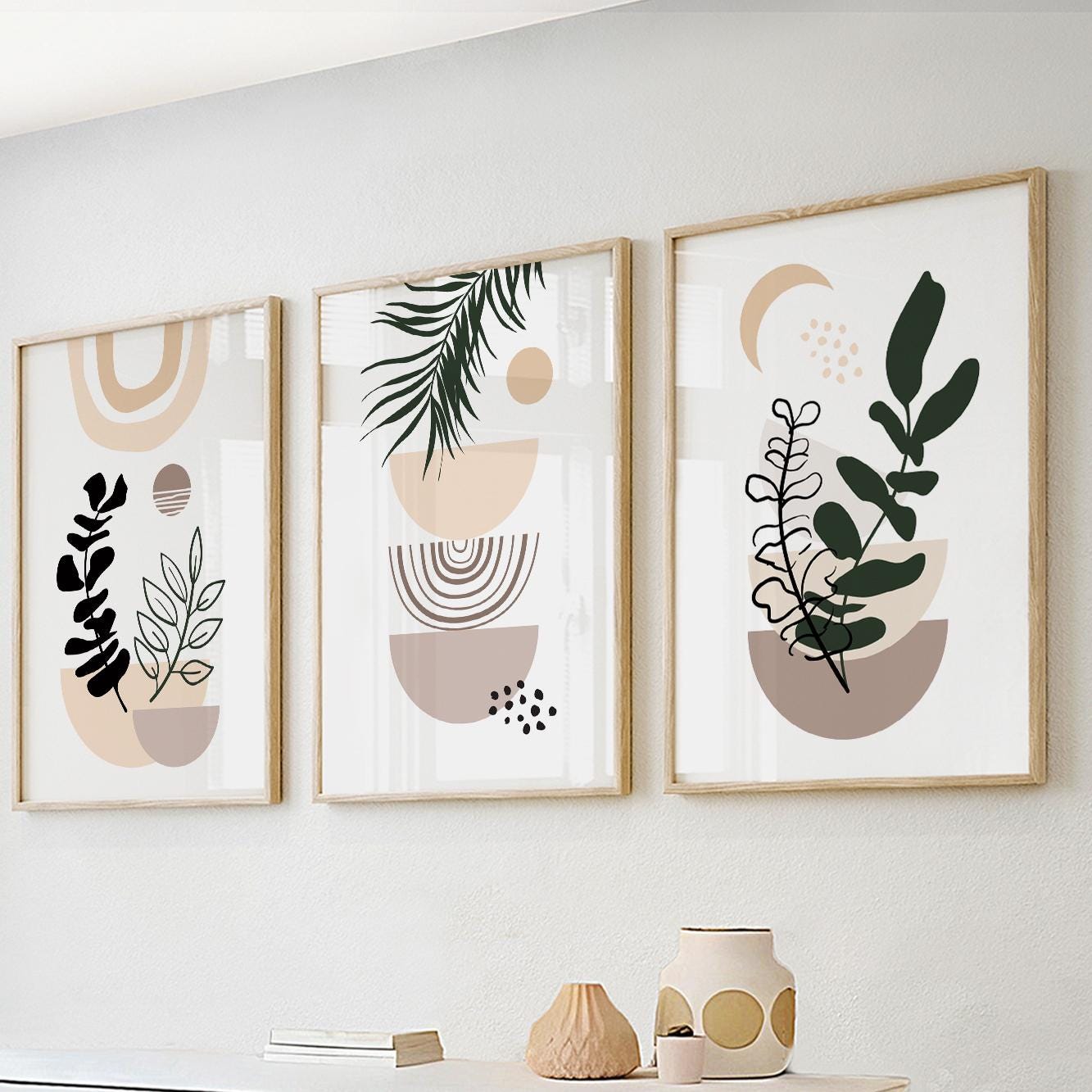 Three framed abstract boho prints with botanical shapes above styled ceramics and books