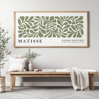 Framed sage green abstract cut-out print styled above a wooden bench with decor accents