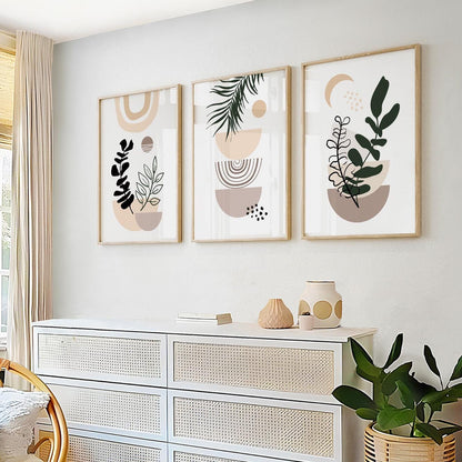 Set of three framed pastel beige boho botanical prints arranged above a dresser