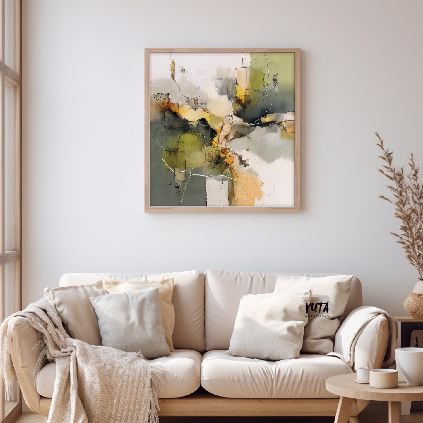 Framed abstract olive green and beige painting centered above a cushioned cream sofa