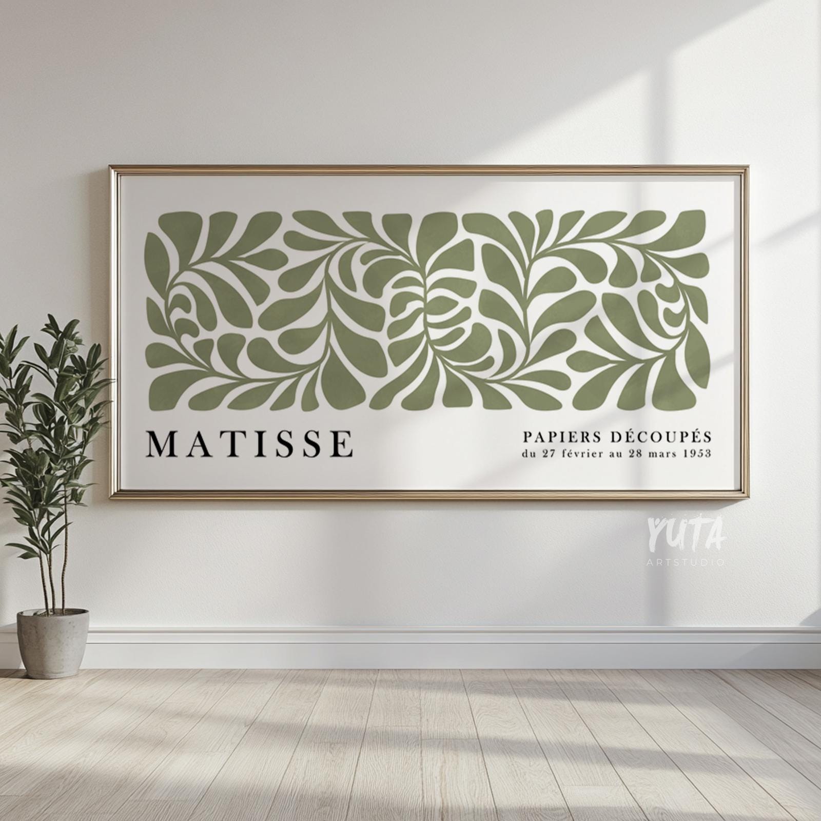 Framed sage green botanical Matisse print hung on a white wall with sunlight streaming in.
