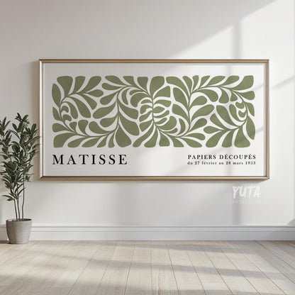 Framed sage green botanical Matisse print hung on a white wall with sunlight streaming in.