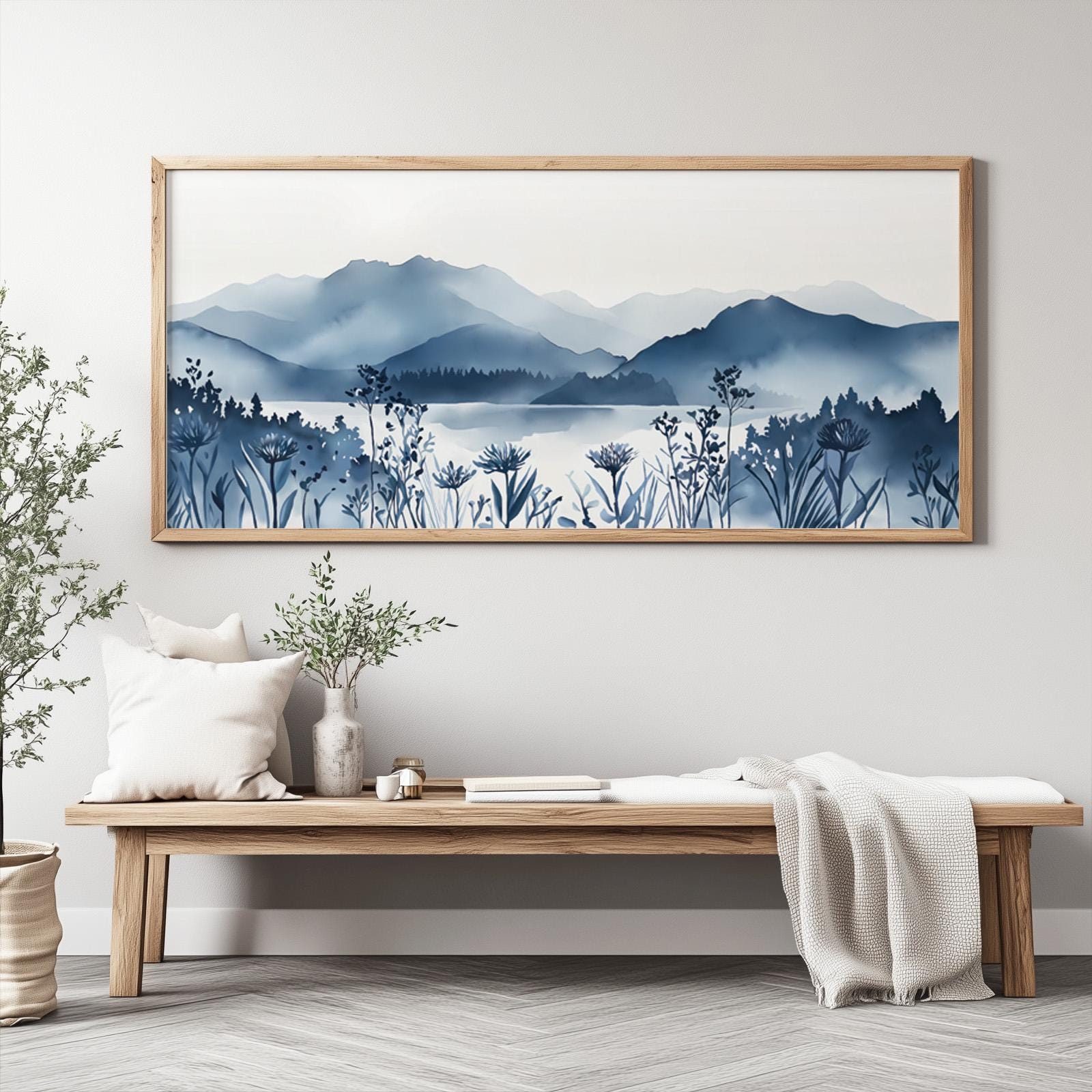 Framed navy mountain lake art with wildflowers displayed above a wooden bench