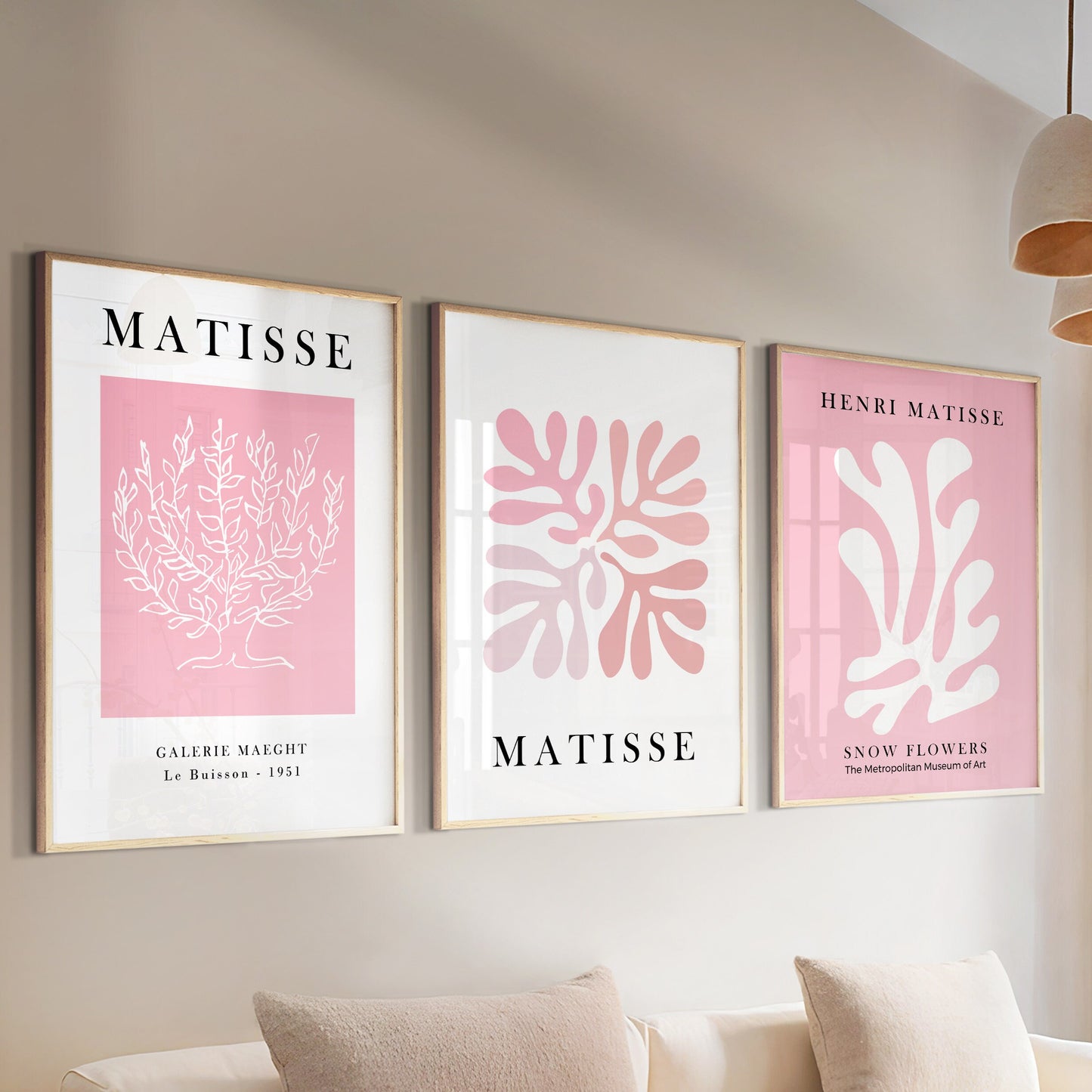 Three framed pink Matisse prints above a sofa, styled with books and a ceramic vase.