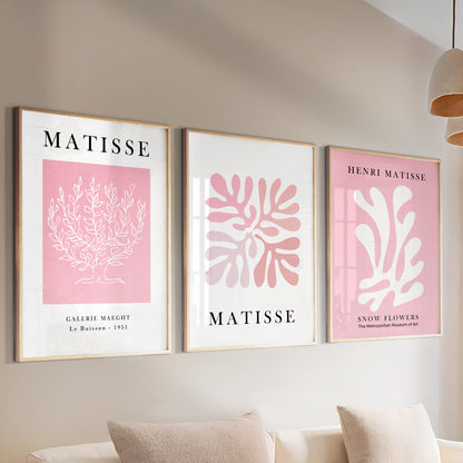 Three framed pink Matisse prints above a sofa, styled with books and a ceramic vase.