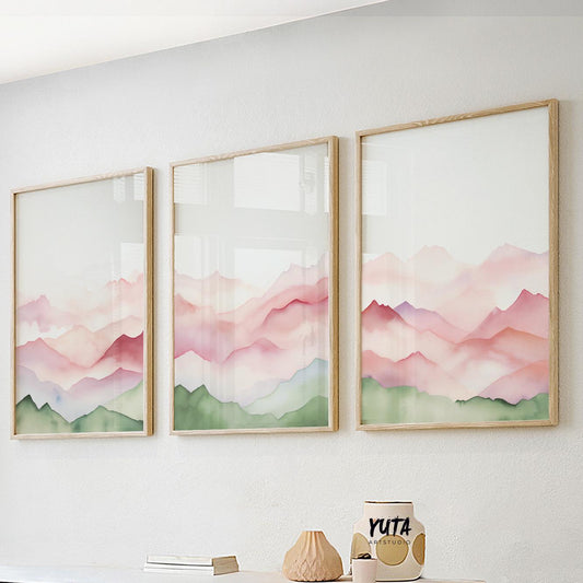 Soft pastel mountain triptych in light wood frames displayed above a modern sofa