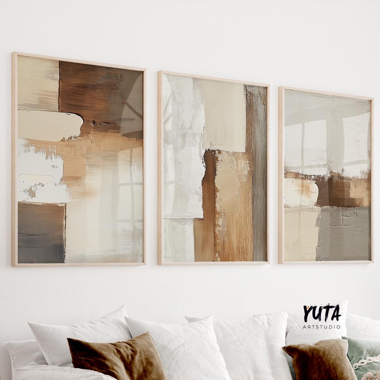 Three minimalist abstract earth tone prints in light wood frames above a white console