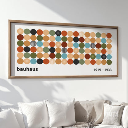 Geometric Bauhaus-inspired print with colorful circles in a natural wood frame above a sofa