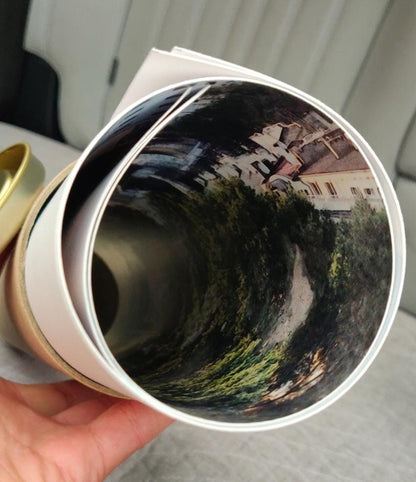 Rolled panoramic art print with tropical landscape details held above a soft surface
