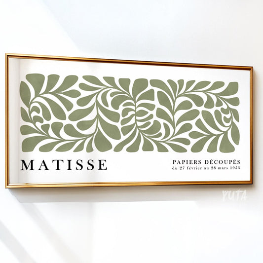 Sage green abstract botanical artwork in a panoramic gold frame against a white wall