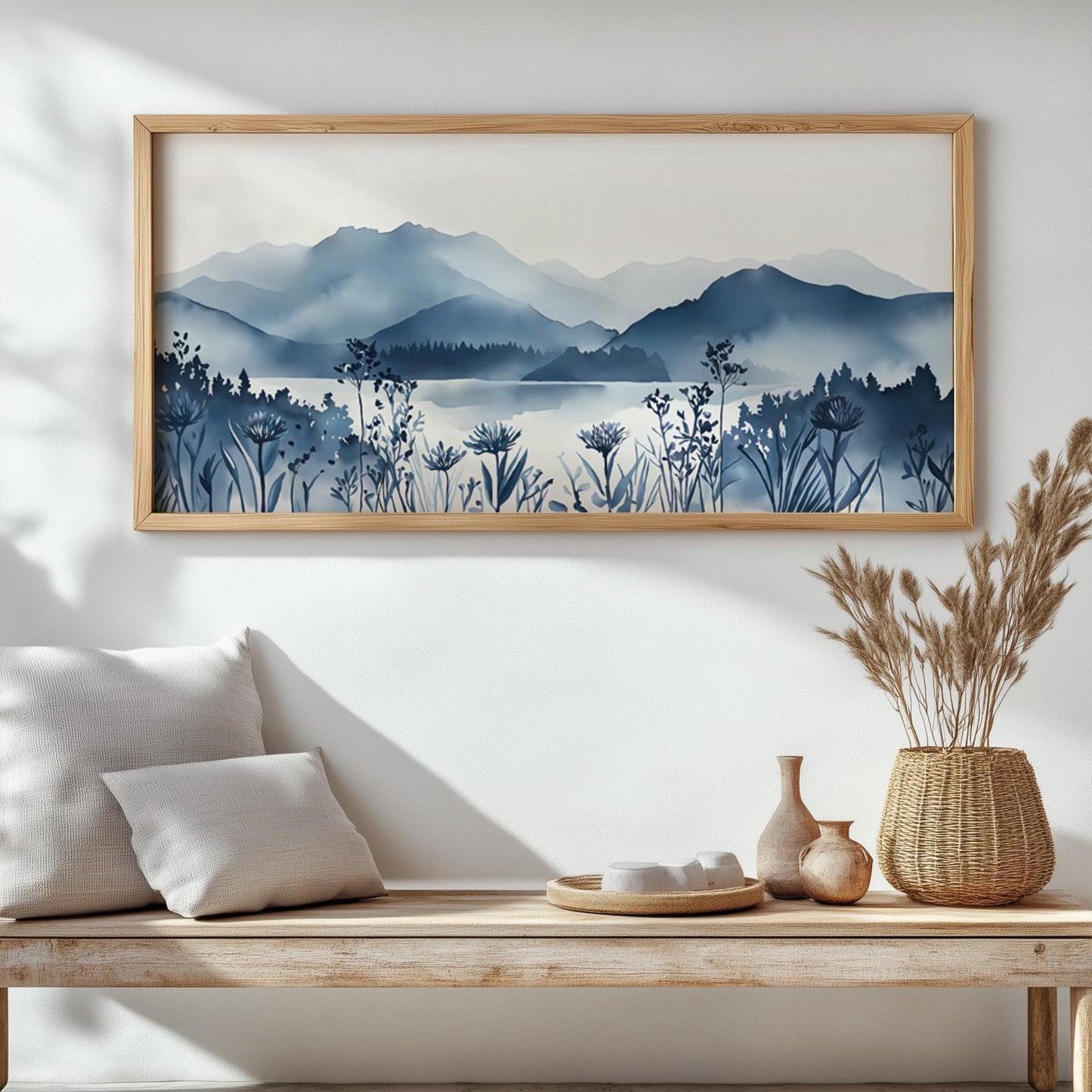Framed mountain lake landscape in navy blue watercolor above a wood bench in natural light