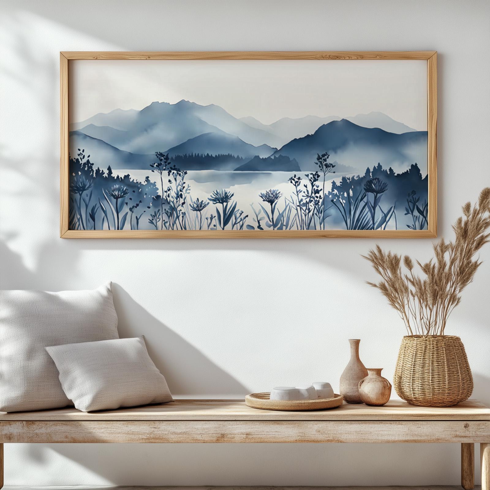 Framed mountain lake landscape in navy blue watercolor above a wood bench in natural light