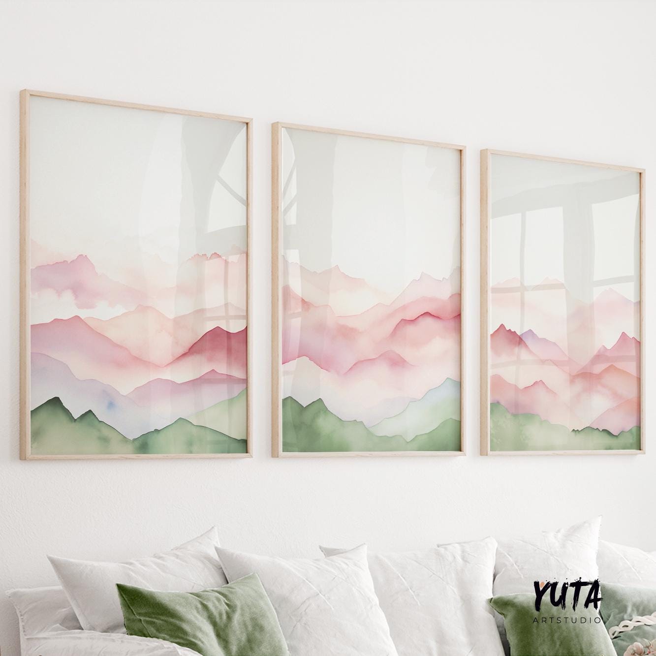 Three framed abstract mountain watercolor prints in sage and blush hues above a white sofa