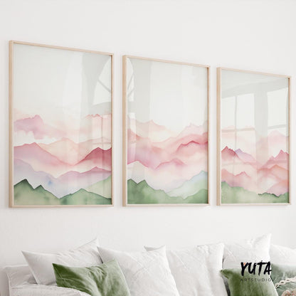 Three framed abstract mountain watercolor prints in sage and blush hues above a white sofa