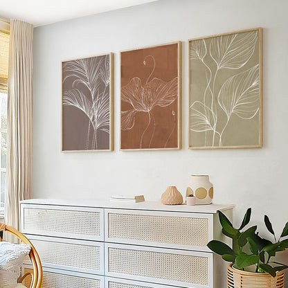 Terracotta botanical wall art triptych with minimalist white floral and leaf illustrations in warm earthy tones.