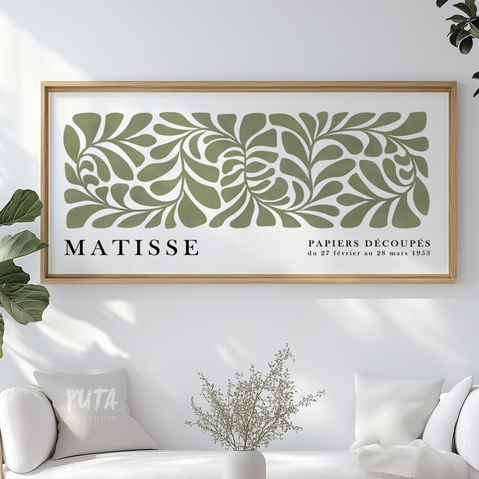 Framed abstract sage green Matisse print with cut-out leaf shapes above a white sofa