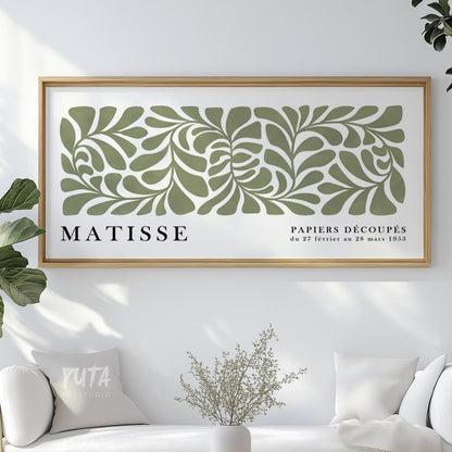 Framed abstract sage green Matisse print with cut-out leaf shapes above a white sofa