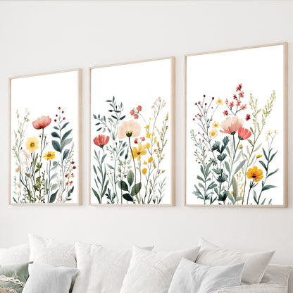 Wildflower wall art set of 3 featuring delicate watercolor meadow flowers in coral, yellow and green on white backgrounds.